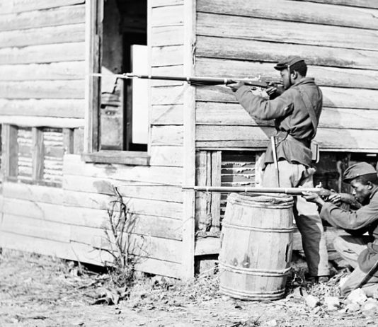 Black soldier fought in the Civil War - in position behind a house with rifles near Dutch Gap Virginia