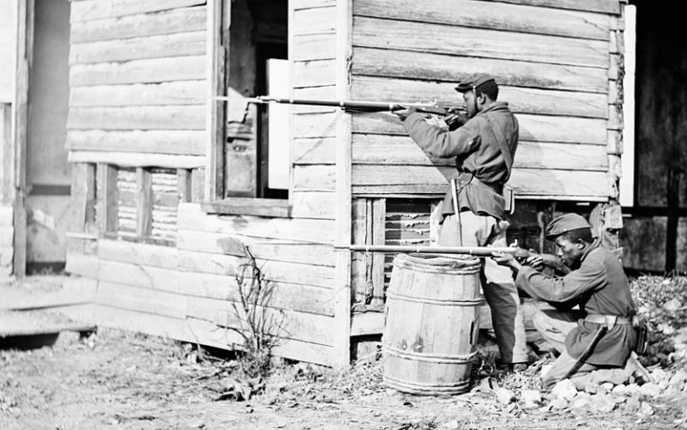 Black soldier fought in the Civil War - in position behind a house with rifles near Dutch Gap Virginia